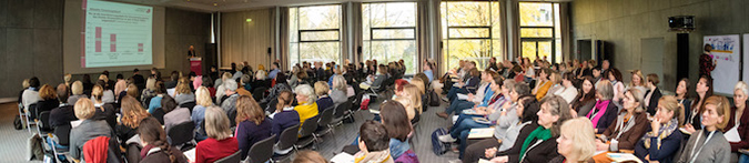 Teilnehmende der Veranstaltung sitzen in einem Saal bei einem Vortrag