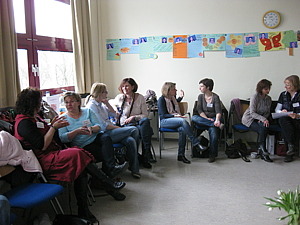Gesprächsrunde, 8 Frauen sitzen auf Stühlen und unterhalten sich