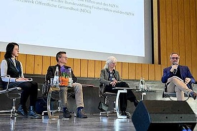 vier Personen sitzen auf einer Bühne