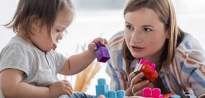 Mutter und Kind mit Downsyndrom spielen mit Bauklötzen