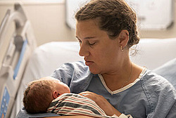 Mutter hält neugeborenes Baby im Arm