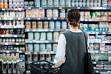 Eine Frau schaut im Supermarkt auf ein Regal mit Muttermilch-Ersatzprodukten.