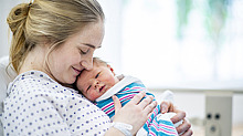 Mutter hält neugeborenes Baby im Arm