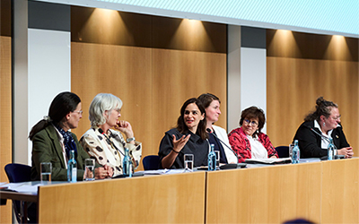 Personen sitzen bei einer Podiumsdiskussion zusammen