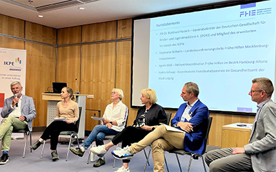 sechs Personen sitzen vor einer Präsentation und diskutieren
