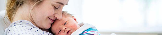 Mutter hält neugeborenes Baby im Arm