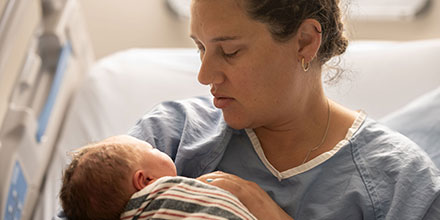 Mutter hält neugeborenes Baby im Arm 