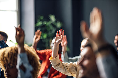 Teilnehmer einer Konferenz heben die Hände