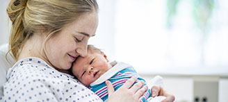 Mutter hält Neugeborenes Baby im Arm