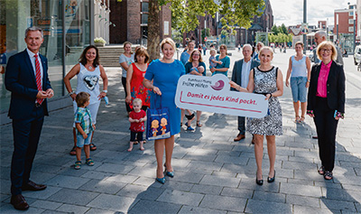 Foto von Personen auf der Straße und Schild mit der Aufschrift "Damit es jedes Kind packt"