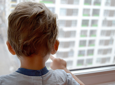Beautiful baby boy with child face posing photographer near wind Kind schaut aus einem Fenster