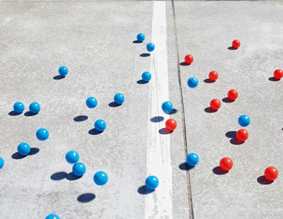 Blaue und rote Kugeln kullern über Fläche mit weißem Strich