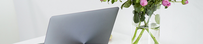 weißer Schreibtisch mit Laptop und rosa Blumen