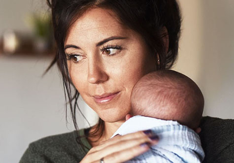 Mutter zu Hause mit einem neugeborenen Baby auf dem Arm
