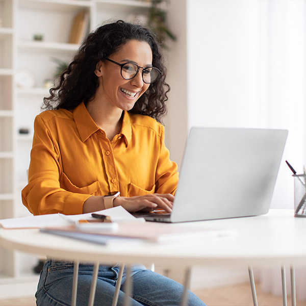 Person sitzt mit Laptop an Schreibtisch