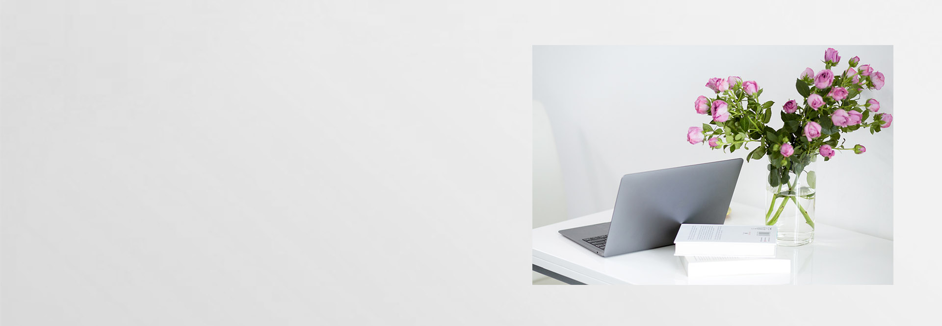 weißer Schreibtisch mit Laptop und rosa Blumen
