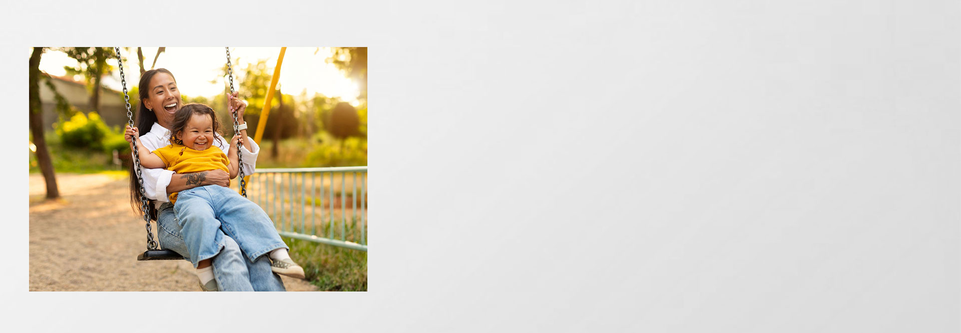 Mutter sitzt mit Kind auf Schaukel