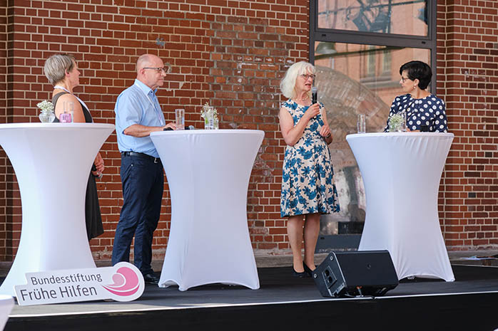 Prof. Dr. Ute Thyen am Mikrofon steht auf dem Podium mit Stehtischen mit Bärbel Derksen, Ulrich Böttinger, und Moderatorin Christiane Poertgen
