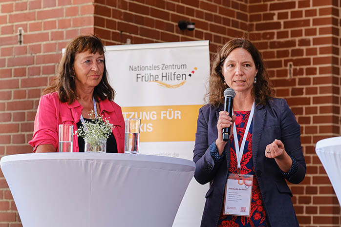 Dr. Meike Nitschke-Janssen mit Mikrofon in der Hand und Prof. Dr. Theda Borde am Stehtisch auf dem Podium