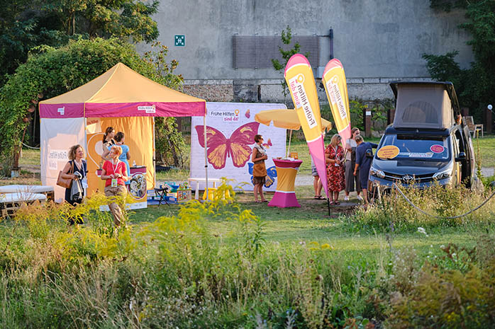 Frühe Hilfen Bus am Infostand „Frühe Hilfen sind da“ auf einer Wiese am Veranstaltungsort