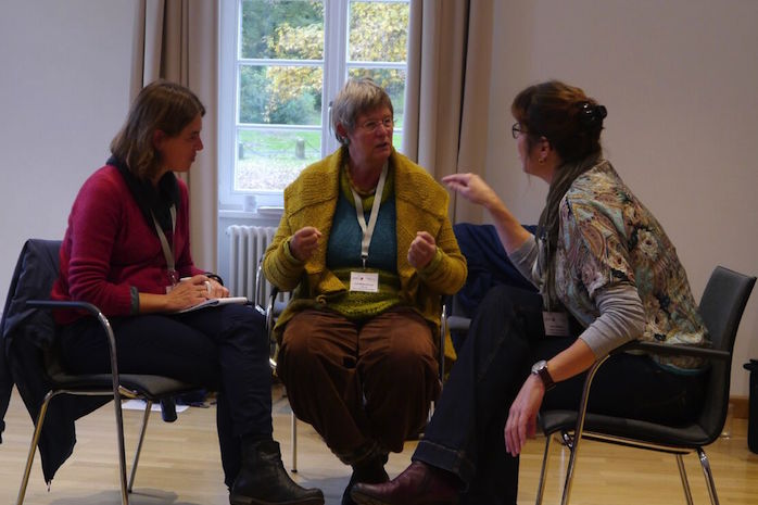 Britta Bacchetta, Christiane Knoop und Anke Bertram sitzen sich auf Stühlen gegenüber und reden