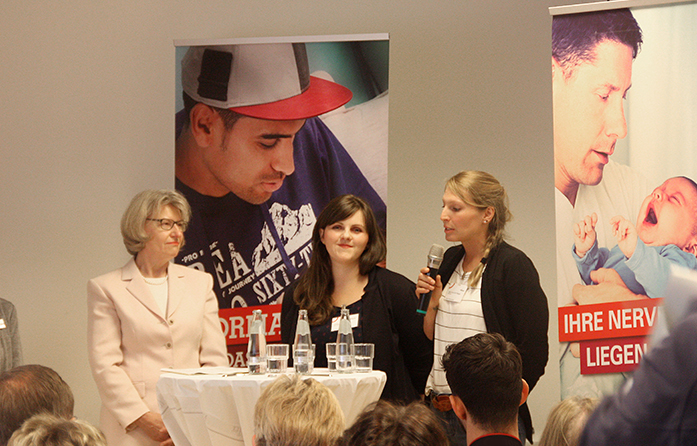 Dr. Heidrun Thaiss mit Babylotsinnen Jasmin Lösche und Juliane Wittekop im Gespräch an einem Stehtisch.