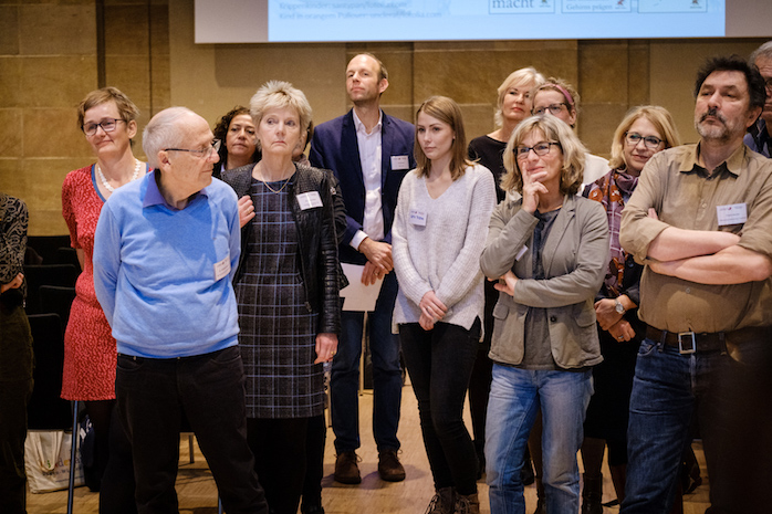 Teilnehmerinnen und Teilnehmer stehen in einer Gruppe zusammen und schauen nach vorn