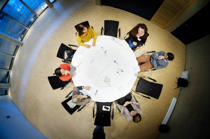 Perspektive von oben auf einen Thementisch mit Teilnehmerinnen und Teilnehmern
