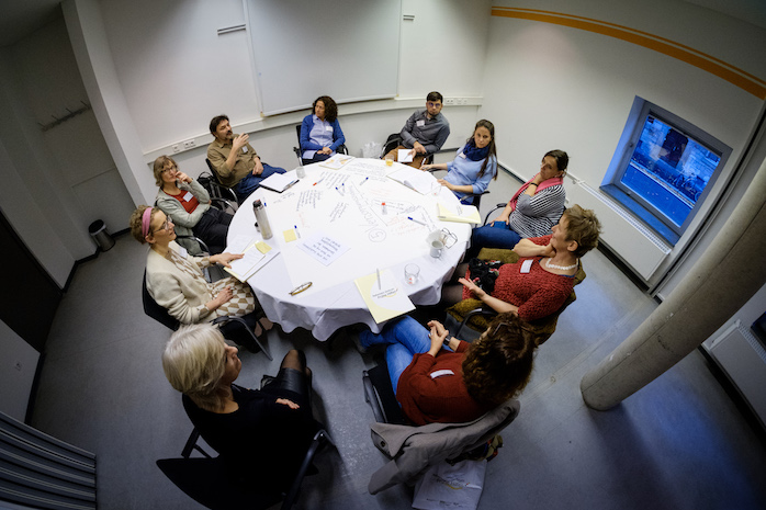 Perspektive von oben auf einen Thementisch mit Teilnehmerinnen und Teilnehmern