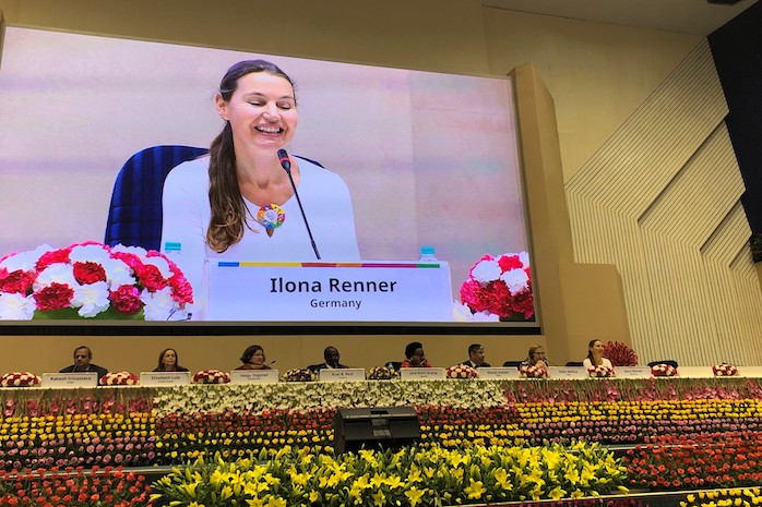 Vortragende sitzen vor großer Leinwand, im Bild Ilona Renner